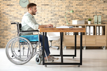 Wall Mural - Young man in wheelchair at workplace