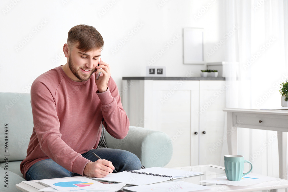 Young man talking on mobile phone while working at home