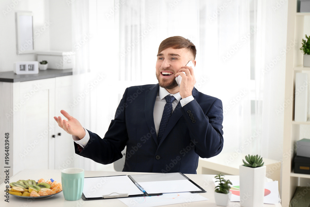 Young businessman talking on mobile phone while working in office