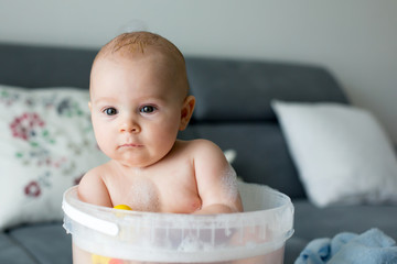 Poster - Cute little four month old baby boy, playing in bucket full with water