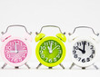 Closeup the colorful alarm clock stacked in row,green alarm clock put at the middle of pink and white color,on white background.