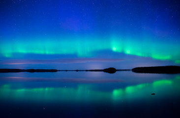 northern lights dancing over calm lake. farnebofjarden national park in sweden.