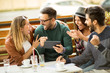 © Mediteraneo - Group of four friends having a coffee together. Two women and two men at cafe talking laughing and enjoying their time using digital tablet.