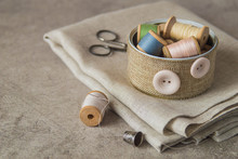 Sewing Accessories And Tools For Needlework. A Piece Of Cloth, A Round Box With Coils Of Threads, Scissors And A Thimble On An Old Table. 