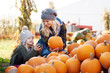 © Connect Images - Young woman and daughter selecting pumpkin from stack at pumpkin patch