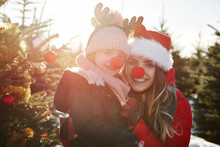 Girl And Mother In Christmas Tree Forest With Red Noses, Portrait