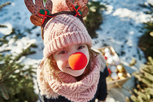 Girl In Christmas Tree Forest With Red Nose, High Angle Portrait