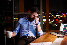 Tired Young Businessman At Office Desk At Night