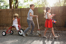 Three Children In Mini Parade, Banging Drum, Riding Tricycle And Using Scooter