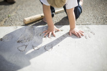 Little Boy Putting His Hand In Handprints Made In Concrete