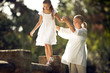 © Erickson Stock - Granddaughter walking on the brick fence with the help of a grandmother