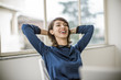 © Erickson Stock - Smiling young businesswoman relaxing after finishing work.