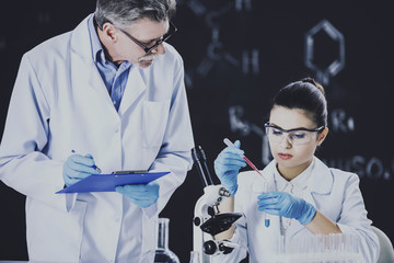 Senior chemistry professor and his assistant working  in  laboratory