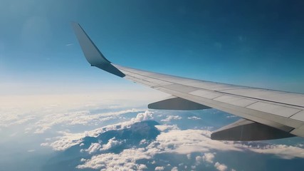 plane wing view of a plane flying over the clouds