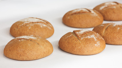 Poster - Several round fresh hot breads on the white tablecloth or shelf in the bakery