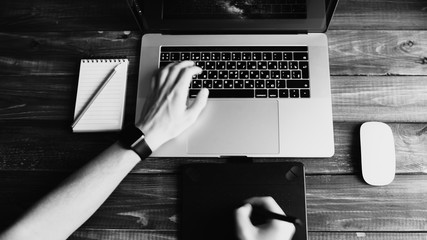 Fototapete - Man designer is working using laptop computer and graphics tablet at home office. Freelance lifestyle workplace
