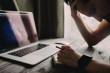 Fototapete - Man is writing on draft notepad and using laptop computer and at home office. Freelance lifestyle workplace