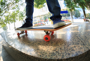 Wall Mural - young skateboarder legs riding skateboard at city skatepark