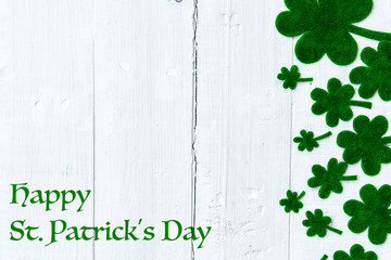 Wall Mural - Happy St Patricks Day message and a lot of green paper clover leaf on white wooden background