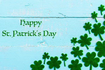 Wall Mural - Happy St Patricks Day message and a lot of green paper clover leaf on Pastel white and blue wooden table background texture.