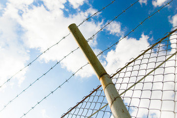 Fence with barbed wire against the blue sky