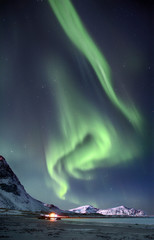polar lights in the sky above the mountains on the northern beach in norway