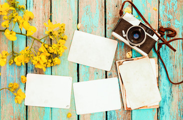 Retro camera and empty old instant paper photo album on wood table with flowers border design - concept of remembrance and nostalgia in spring. vintage style