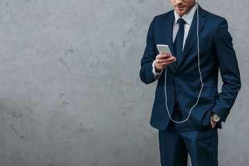 cropped shot of businessman listening music with headphones and smartphone