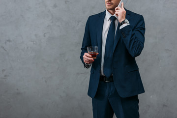 Wall Mural - cropped shot of businessman with glass of whiskey talking by phone