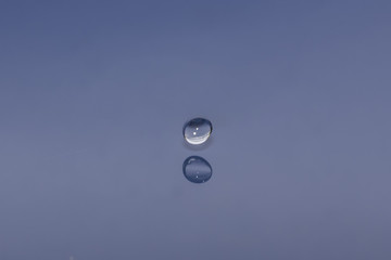 Wall Mural - drop of water liquid with splash isolated. the drop explodes in the water sending spray to the sides and circle ripples around it. the water is blue