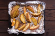 Fried russet potato on tray with aluminium foil on rustic wooden background