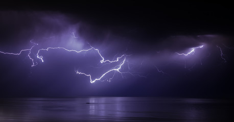 lightning bolts reflection over the sea. taken during a thunderstorm over the ocean with clouds in the background