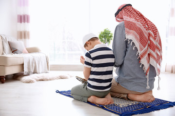 Wall Mural - Muslim man praying with son at home