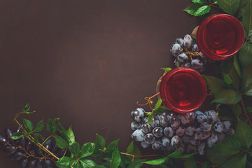 Still life with wineglasses, bottles, grapes and leaves on brown wooden desk. Toned