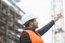 Man With Wearing Safety Vest And Hard Hat At Construction Site