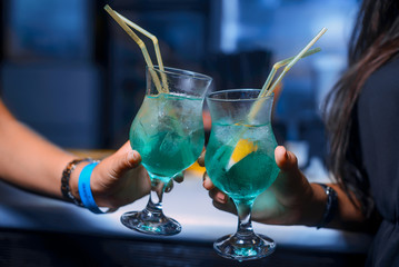 two alcohol cocktails keeping in girls hands in the night club