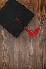 Wall Mural - Top view of square academic cap on wood background
