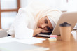 © freeograph - Arab woman wearing a headscarf sitting tired at work.