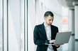 © F8  \ Suport Ukraine - Young businessman working on laptop in hands standing in office