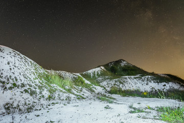 Starry night sky over the white cretaceous hills. Night natural landscape with chalk ridges. Belgorod region, Russia.