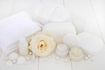 Wall Mural - Spa beauty treatment products with a rose, ex foliating salt, moisturising cream, body lotion, sponges, wash cloths, shells and decorative pearls on white wood background.