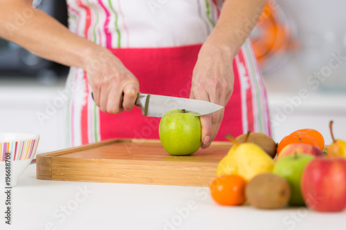 Zdjęcie XXL zbliżenie na dojrzałych kobiet ręce krojenie jabłka na desce do krojenia