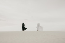 Black Vs White Contrast Concept Of Two Humans Draped In Fabric In The Desert