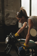 Young Female Working On Restoration Of Old /vintage Motorbikes In Old Rusty Motorbike Garage/workshop