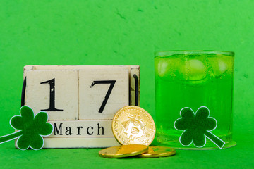 Wall Mural - Block calendar for St Patrick's Day, March 17, with green clover leaf, green water and gold bitcoin on bright green Mulberry paper background