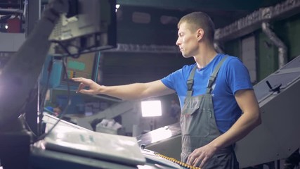 Engineer works with industrial equipment using touchscreen.