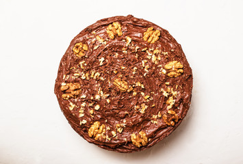 Wall Mural - Homemade chocolate cake with nuts, white background, top view