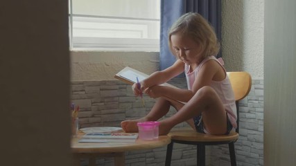 child girl drawing by watercolor at home in slow motion.