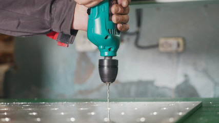 Industrial drilling machine - worker makes holes in metal