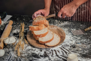 Wall Mural - Man preparing buns at table in bakery, Man sprinkling flour over fresh dough on kitchen table